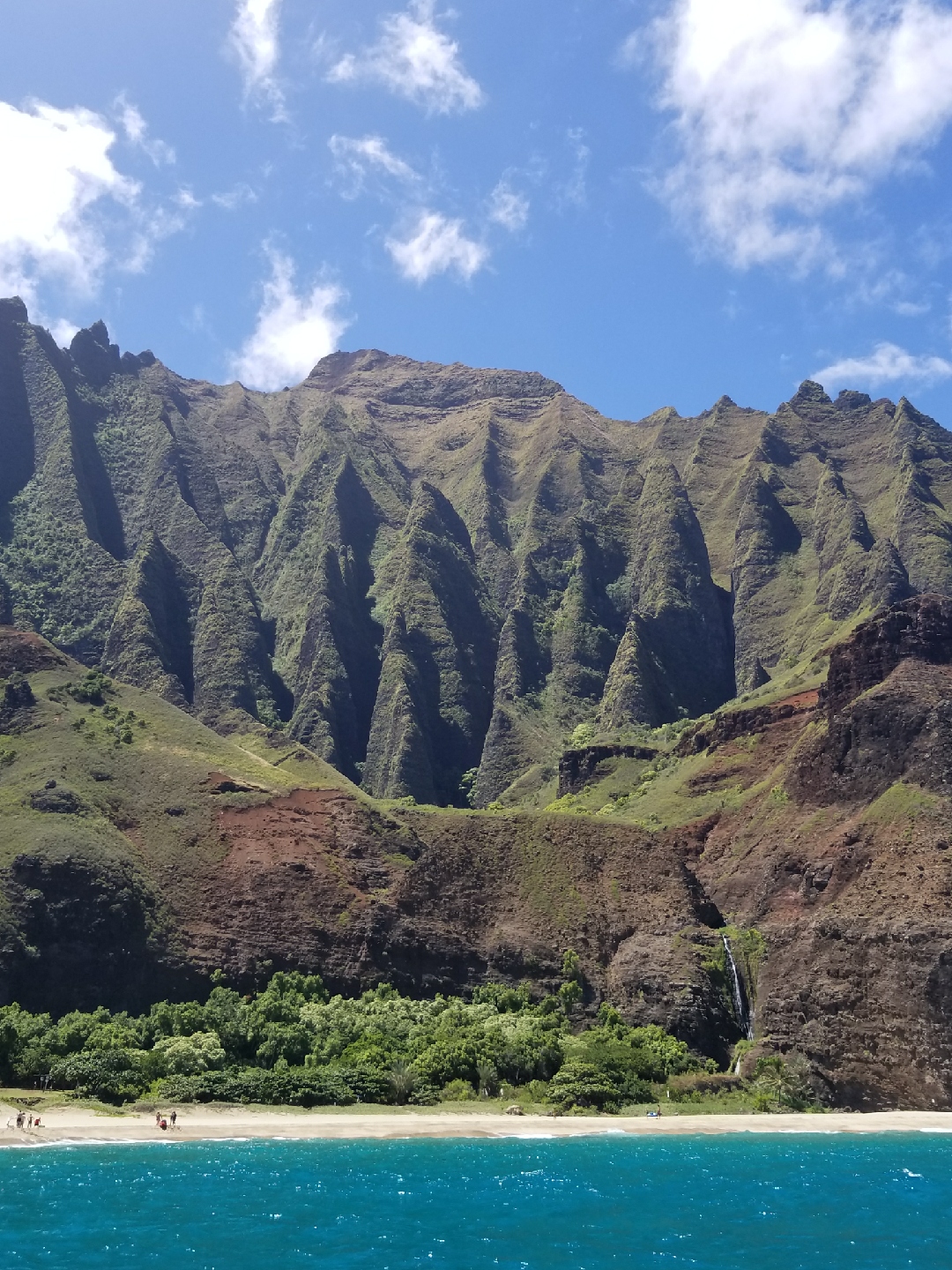 People on a beach next to a waterfall